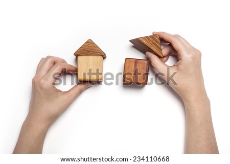 A female hand hold(pick up) the wood block among the wood blocks like two house(real estate) isolated white, top view at the studio.