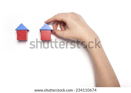 A female hand hold(pick up) the wood blocks like house(real estate) isolated white, top view at the studio.