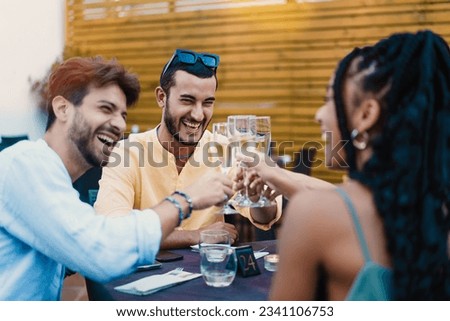 Toast of Friendship at the Restaurant - Trendy young man leads a champagne toast with diverse friends, embodying joy and camaraderie.
