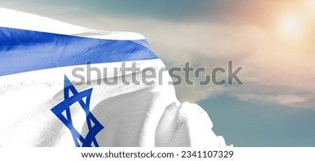 Israel national flag cloth fabric waving on beautiful sky Background.