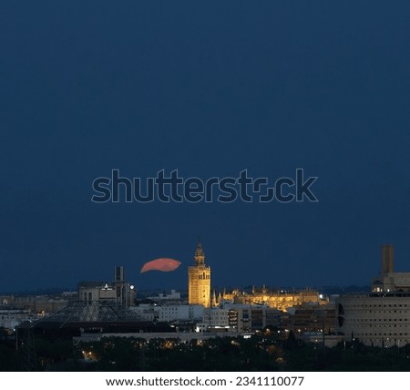 Night Glow: The Mystical Supermoon Rises Behind the Giralda of Seville