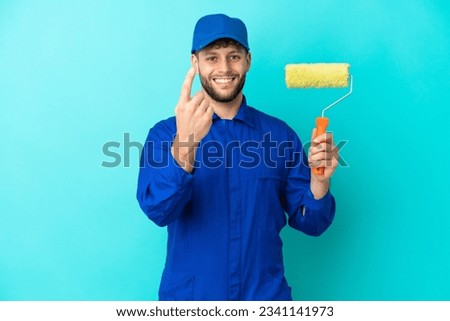 Painter caucasian man isolated on blue background doing coming gesture