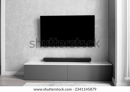 Part of the interior of the living room with a TV on the wall, hifi equipment, Sound bar, gray cabinet. TV and music system in the interior. Royalty-Free Stock Photo #2341145879