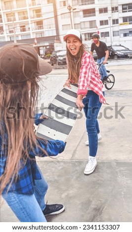 Angry girls fighting for a skateboard in skate park. friends doing wrestling parody.