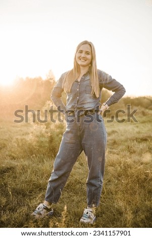 Girl having fun in green grass in field at sunset. Young woman walking spending time together with family in spring nature. Family holiday outdoors. Female smiling in summer park. Sunset scene.