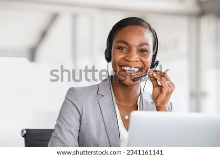 Portrait of smiling african american customer care service with headset attending calls in office. Black mature telemarketing agent working in call center and looking at camera with copy space.  Royalty-Free Stock Photo #2341161141