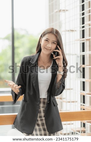 Beautiful successful asian businesswoman holding mobile phone using smartphone in office chatting with business mannequin vertical image