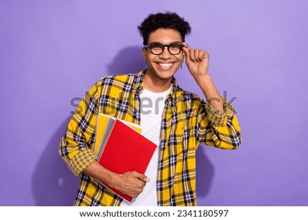 Photo of positive cheerful guy wear plaid yellow shirt arm spectacles holding copybooks isolated violet color background
