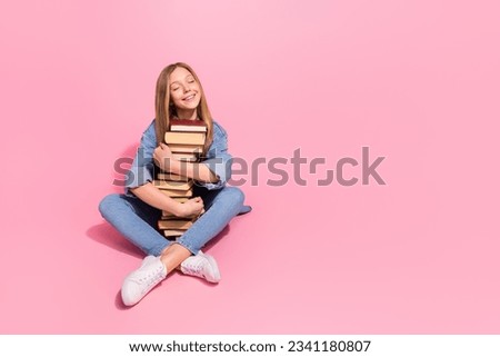 Photo of lovely dreamy satisfied girl wear stylish denim clothes hug pile stack books sit empty space isolated on pink color background