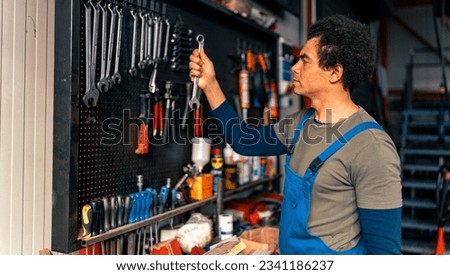 A master in overalls puts tools on the wall, which is very organized