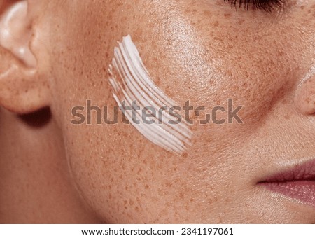 Close-up shot of female skin with freckles with white cream Royalty-Free Stock Photo #2341197061