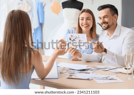 Young couple with pictures planning their wedding in office