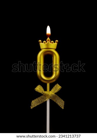 Burning gold birthday candle with crown isolated on black background, number 0.