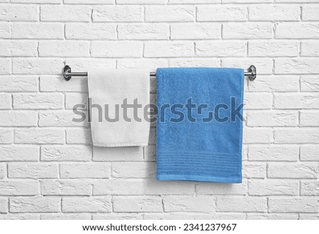 Rack with clean soft towels on brick wall