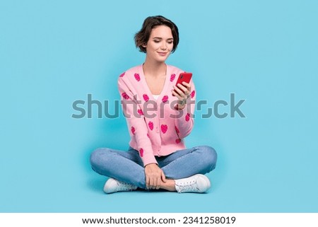 Full body photo of gorgeous positive lady sit floor crossed legs use smart phone chatting isolated on blue color background