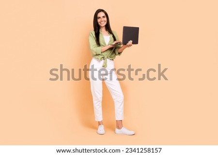 Full length photo of lovely positive satisfied woman wear green shirt holding laptop write email isolated on beige color background