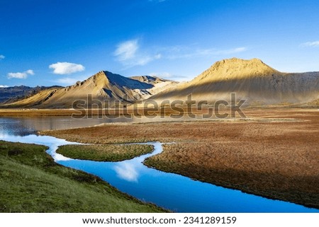 A river in iceland with the shadow of clouds on mountains