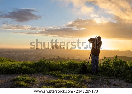 A silhouette of a photographer over looking Downtown Los Angeles, California at sunset during spring