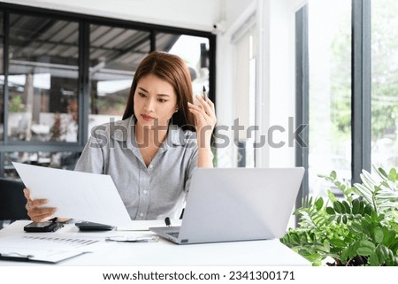 Young thoughtful Asian business woman executive manager wearing shirt working in modern office, taking notes and thinking of professional plan, project management, considering new business ideas. Royalty-Free Stock Photo #2341300171
