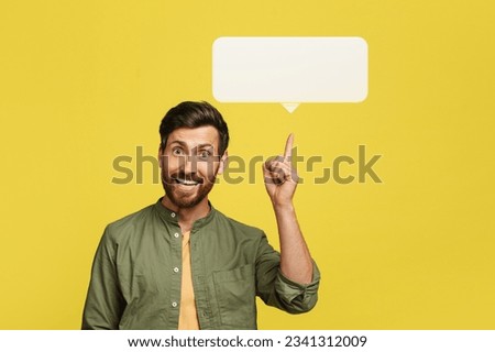 Positive handsome bearded man experiencing AHA moment, sharing great creative idea, pointing finger up at white empty communication bubble over yellow studio background, blank space Royalty-Free Stock Photo #2341312009