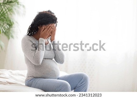 Sad Black Pregnant Woman Crying At Home, Having Maternity Depression, Suffering Hormonal Changes During Pregnancy, Desperate Lady Sitting On Bed In White Bedroom Covering Face With Hands, Copy Space Royalty-Free Stock Photo #2341312023