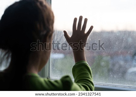 child girls are standing in the dark, looking out the window, sad mood