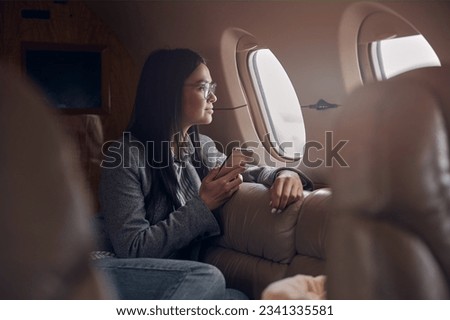 Happy smiling beautiful business woman in private jet Royalty-Free Stock Photo #2341335581
