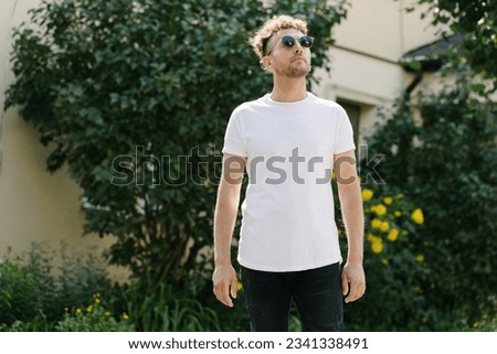 Hipster handsome male model wearing white blank t-shirt with space for your logo or design in casual urban style