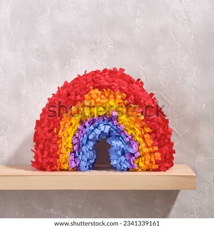 A colorful bright festive rainbow pinata on a gray concrete background. Image of festive composition.