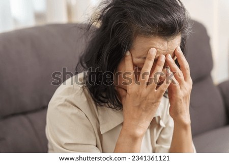 Sad middle age Asian woman touching forehead having headache suffering from migraine. mature asian woman feeling sick or depression Royalty-Free Stock Photo #2341361121