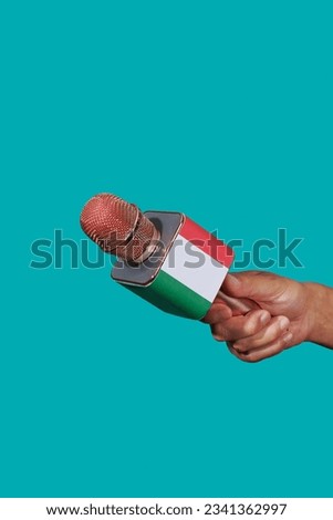 closeup of a man holding a microphone patterned with the flag of italy on a blue background