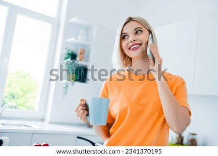 Photo of charming lady drinking latte cappuccino talk with friends using gadget in modern kitchen rent apartment