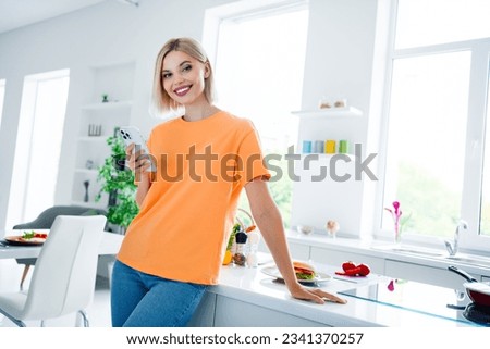 Photo of charming lady cooking dinner in dining room kitchen use gadget chatting chef friends inviting