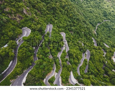 drone shot aerial view top angle beautiful mountain ghat road hairpin bends dense forest natural scenery wallpaper background yercaud tamilnadu india tourist destination lust woods curving pathway  Royalty-Free Stock Photo #2341377521