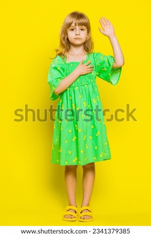 I swear to be honest. Sincere responsible child girl kid raising hand to take oath, promising to be honest tell truth be polite, keeping hand on chest. Preteen children on yellow background. Vertical Royalty-Free Stock Photo #2341379385