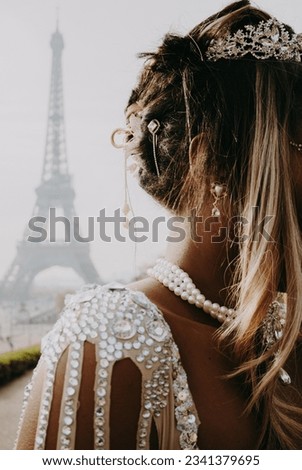 Potrait of stylish and fashionable black women with golden hairpiece, pearly necklace and sparkling dress details with eiffel tower background