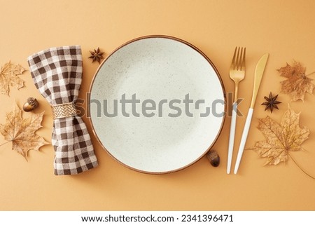 Fall table arrangement idea. Top view cpmposition of blank plate, cutlery, checkered napkin, dry maple leaves, acorns, anise on pastel brown background