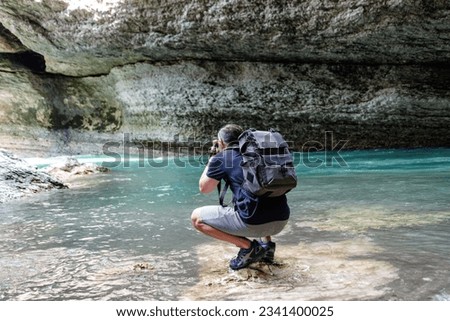 one young adult male tourist taking pictures of mountain river with rocks in thailand