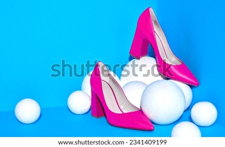 Glamourous red high heels with pointed toe placed in the corner of blue-colored three-dimentional background on white textured spheres. Mock up for design advertising for shoe store.Copy space.