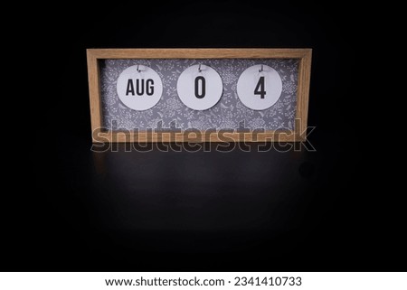 A wooden calendar block showing the date August 4th on a dark black background, save the date or date of event concept