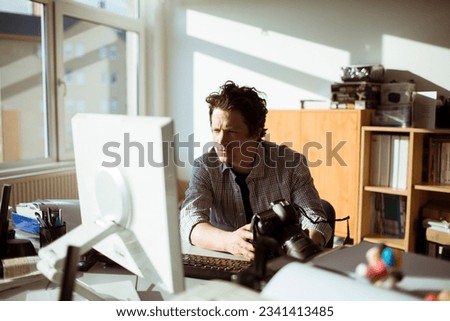 Young male photographer working for a media company in an office