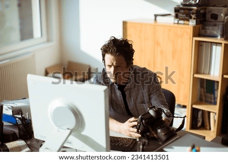 Young male photographer working for a media company in an office