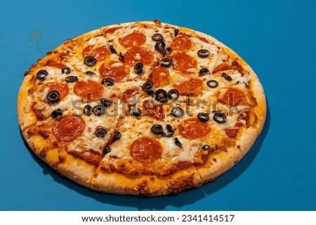 Pepperoni and olive pizza on blue background