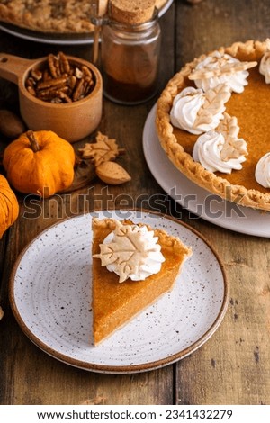 Traditional pumpkin pie for Thanksgiving topped with whipped cream with a slice taken out