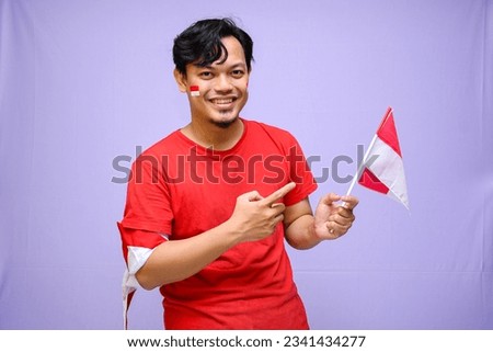 Indonesian man celebrate indonesian independence day on 17 August, wearing red shirt. isolated on purple background. copyspace