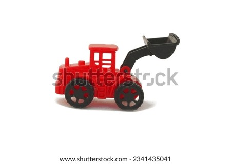 Child's toy pose in the form of a miniature red loader heavy equipment made of plastic with isolated white background