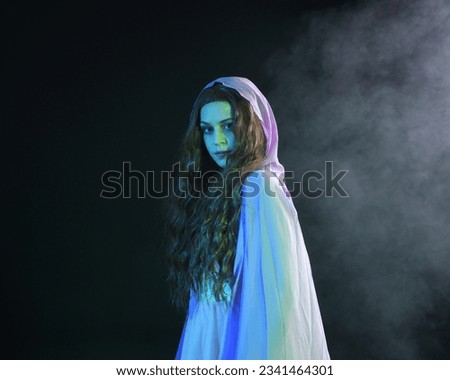 Close up  portrait of beautiful brunette woman wearing  a gown with purple fantasy cloak, posing with arms reaching out. isolated on dark studio background with cinematic colourful lighting.