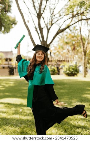 young woman celebrating graduation in a black and green gown