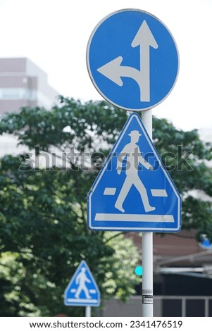 Blue traffic sign on Japan road showing direction signs and pedestrian crossings                                Royalty-Free Stock Photo #2341476519