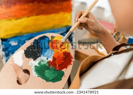 Close up hand Asian woman artist working on painting with brush and variant acrylic color. Female artist painter on canvas in creative studio as art concept Royalty-Free Stock Photo #2341478921